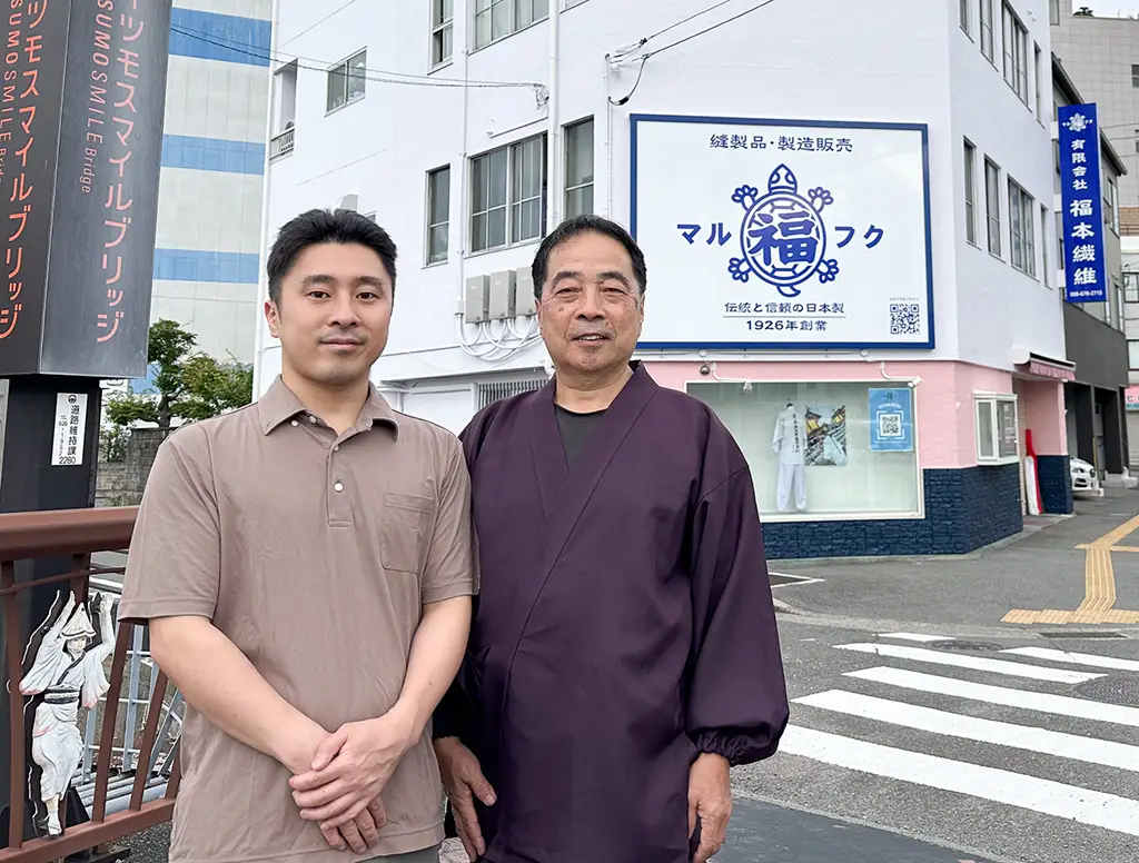 リニューアルした福本繊維のビルの前で佇む親子二代